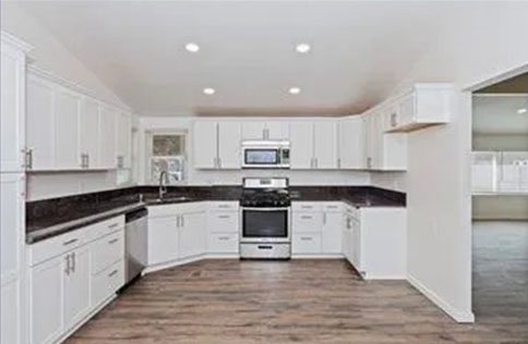 A kitchen with white cabinets and black counter tops.