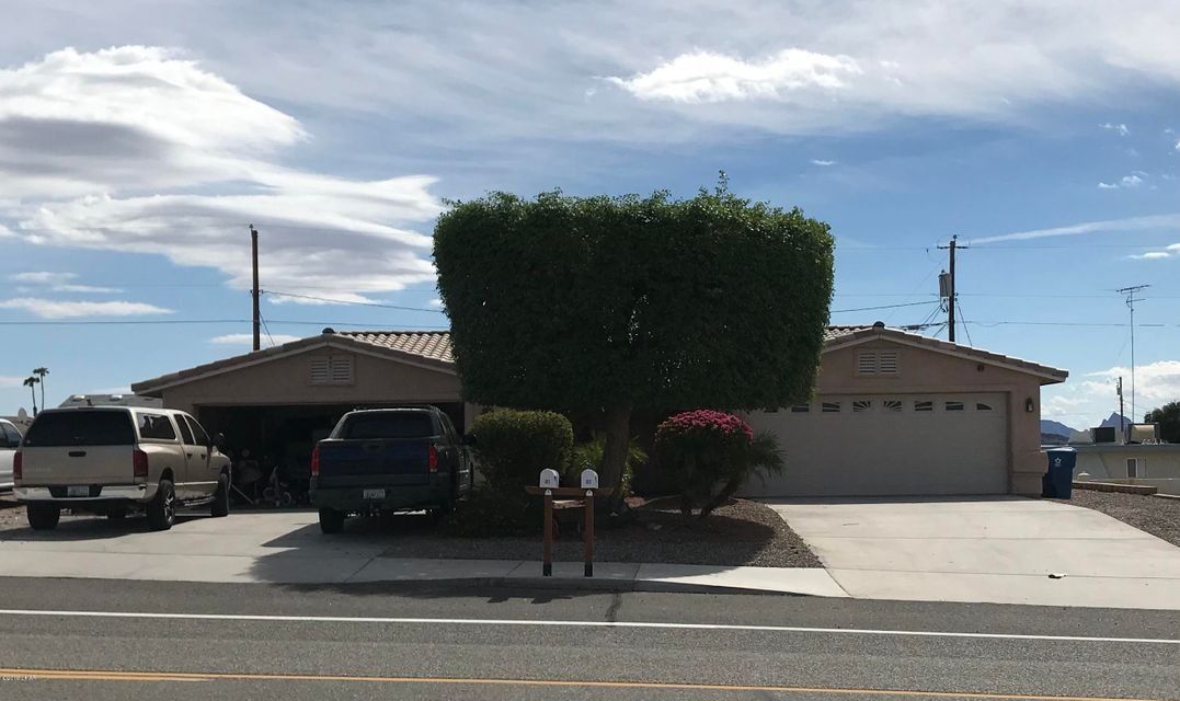 A man standing next to a tree on the side of a road.