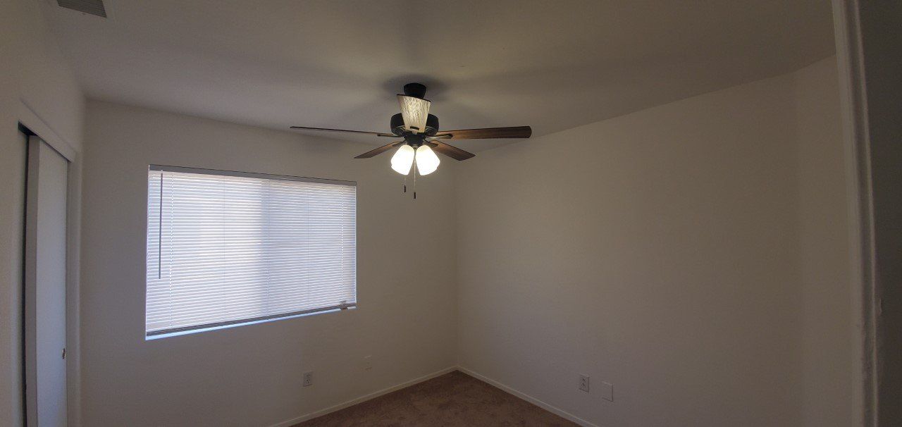 A room with a ceiling fan and a window.